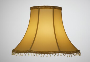 Close up of a gold colored lampshade with beaded trim against a plain white background studio shot