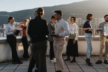 A group of business colleagues is gathered on a high rooftop, brainstorming and discussing project...