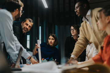A diverse group of business people brainstorming in a corporate office. The image highlights...
