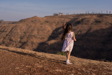 Little girl throwing stones playfully in the valley of hills