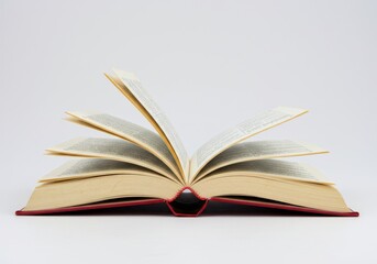 Fototapeta premium An open book with red cover and white pages displayed against a plain white background in a studio shot
