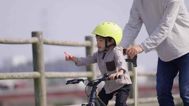 自転車の練習をする5歳の男の子とサポートする父親	
