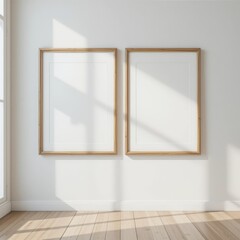 Two elegant, empty picture frames hang on a pristine white wall, casting soft shadows on the warm, polished wooden floor beneath them.