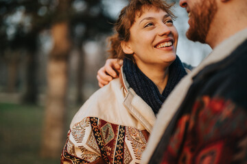 A cheerful couple embraces and shares a joyful connection amid a beautiful outdoor setting,...