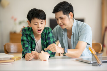 Fototapeta premium A father is teaching his son how to save money by putting money in a piggy bank.