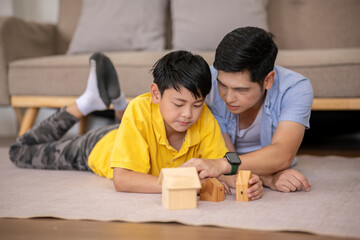 The father plays with his son on the floor in the living room.