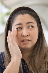 Chubby Asian middle aged woman suffering from irritated eye, concept image for optical health care,...