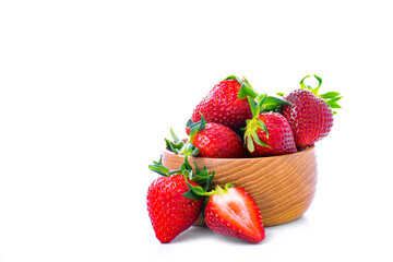 Fresh ripe strawberries in a wooden bowl with half a strawberry on a white background. 