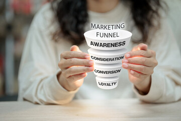A person holding a floating 3D marketing funnel with stages: Awareness, Consideration, Conversion,...