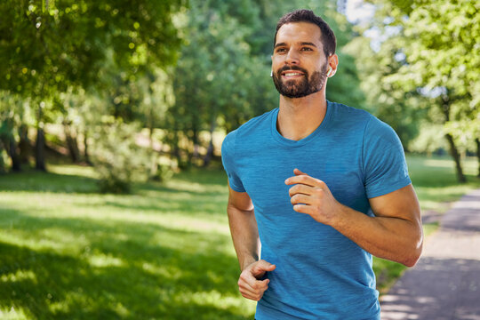 Handsome man running in park with earphones