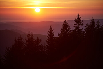 Sun sets in blaze of golden and orange hues, illuminating sky and casting warm glow over landscape....