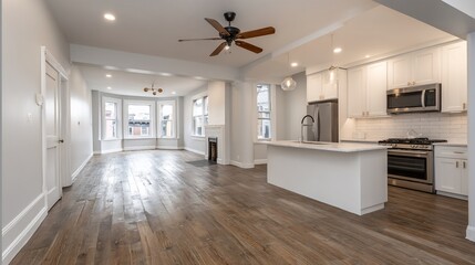 Interior home view of a kitchen and living room, wood floor, bright light, and gray paint