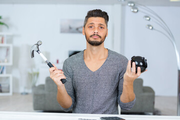 man holding hammer and piggybank