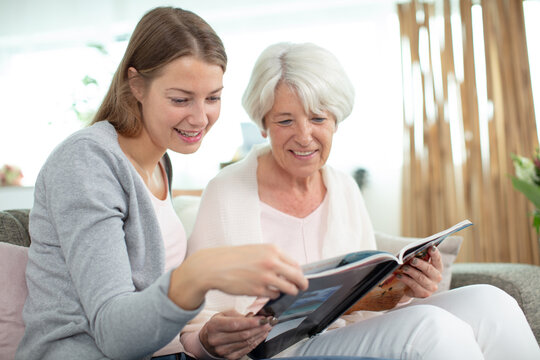 elderly woman with granddaughter looking at memory family photo album