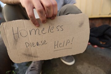 Man with sign Homeless please help and money outdoors, closeup