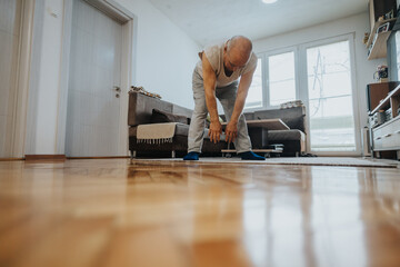Man performing stretching exercises at home in a well-lit living room, highlighting an active and healthy lifestyle in a comfortable setting.