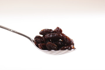 a spoon of dried raisin isolated on white background