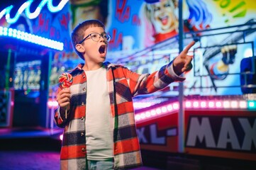 Fototapeta premium A handsome and happy boy is having fun in the amusement park