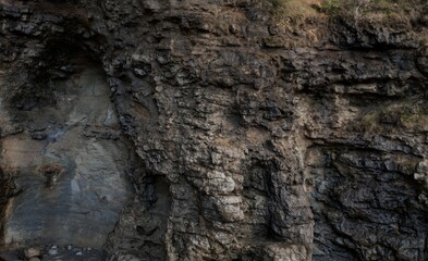 Close-up view of rough, dark, layered rock face with a crevice