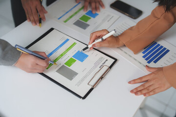 Business team collaborating in an office, analyzing financial charts and graphs, discussing monthly...
