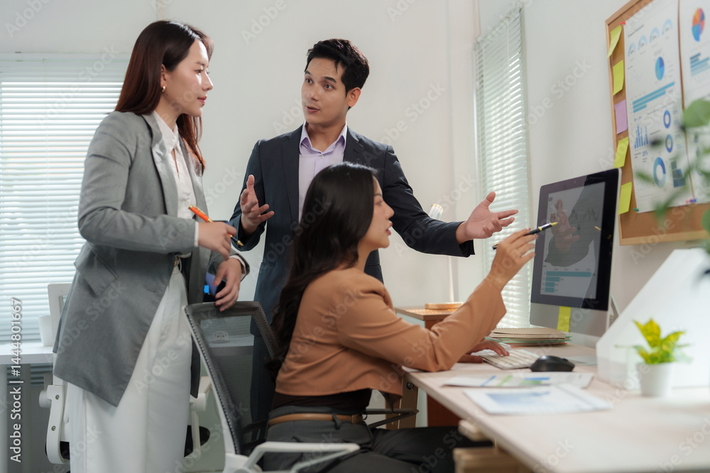 Poster professionals engaging in a productive discussion around a computer screen in a contemporary office 