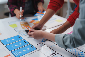 Designers working together on a mobile app project, arranging and discussing interface prototypes. Hands on collaboration highlights the creative process in modern app development