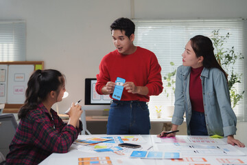 Asian businessman presenting a mobile application screen mockup prototype to a team in a modern...