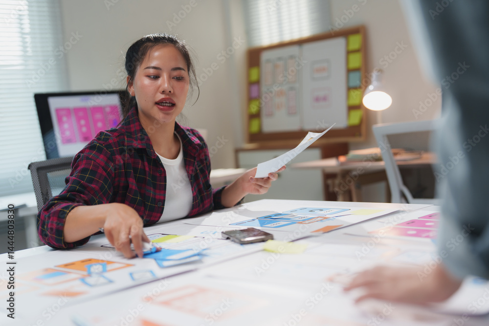 Poster asian female web designer collaborating with a colleague in a modern office, discussing mobile app u