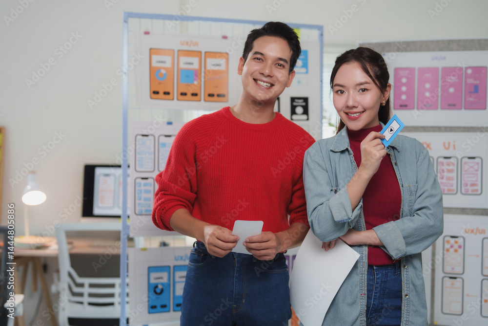 Poster two young asian ux designers smiling while presenting mobile application wireframes and prototypes o