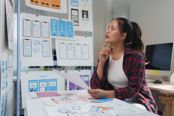 Young professional web designer reviewing mobile application wireframes, contemplating design...