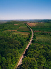 A breathtaking aerial shot vividly showcasing a beautifully meandering road surrounded by lush,...