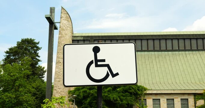 Sign with international symbol of access depicting person in wheelchair displayed on street. Sign indicates accessibility for individuals with disabilities