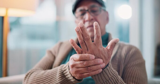 Arthritis, medical and senior man with hand pain, injury or muscle sprain in living room at nursing home. Osteoporosis, parkinson disease and closeup of elderly male person with wrist inflammation.