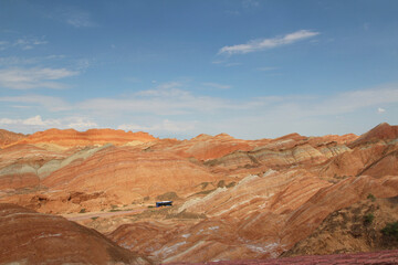 Scenery of Zhangye Danxia National Geopark (Rainbow Mountains) and a bus on the road in Gansu, China