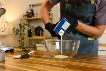Close up of man pouring cream into glass mixing bowl, beginning the homemade butter