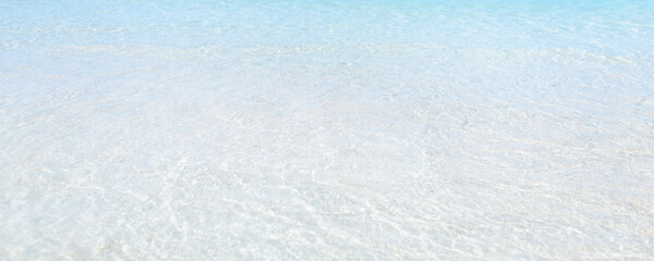 Close-up view of calm clear water over white sand at a tropical beach, perfect for wellness, travel, relaxation, spa, copy space backgrounds and peaceful minimalist summer visuals.