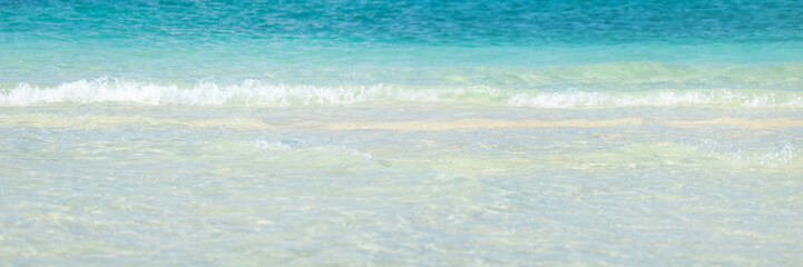 Obraz na płótnie Canvas Scenic view of calm turquoise sea with gentle waves on a pristine sandy shore, ideal for travel, tropical vacation, wellness, spa, beach background, banner use and peaceful lifestyle visuals.