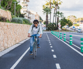 Young African American Man Biking on Urban Cycle Lane - Man riding bicycle alone on a protected...