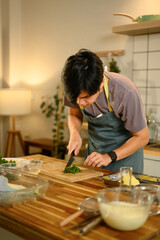 Man preparing fresh herbs on wooden cutting board for making compound butter in a kitchen