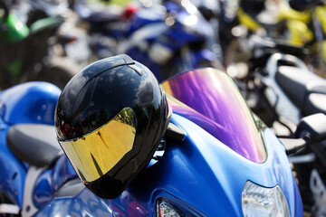 Closeup black moto helmet on motorcycle handlebars against blurred background