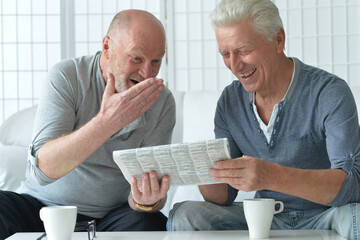 Two old men sitting at table and discussing news