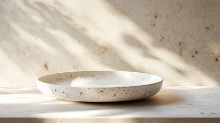 Speckled White Ceramic Bowl on Beige Table with Sunlight Shadows
