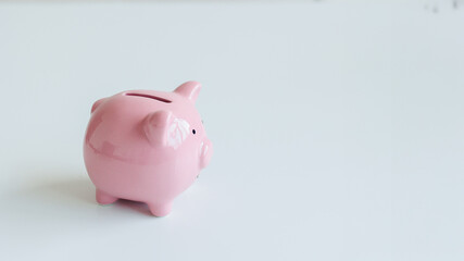 Cute pink piggy bank sitting on a white surface, symbolizing saving money and financial planning for individuals and families