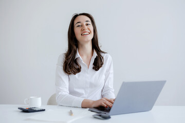 Smiling woman working at a laptop in a bright, modern office space during the day