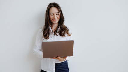Woman smiles while using laptop in a bright room during a work session