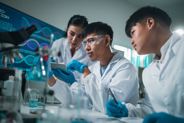 Modern medical scientists collaborate in a high-tech laboratory, analyzing chemical reactions and...