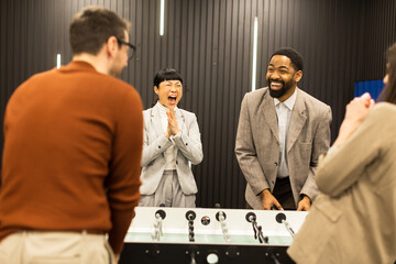 Joyful celebration among friends during a foosball game in a stylish indoor setting