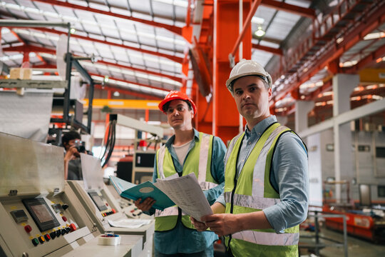 Industrial technicians collaborate in factory, focusing production systems, equipment operation, machinery maintenance quality control, engineering tasks, technical documentation, project management