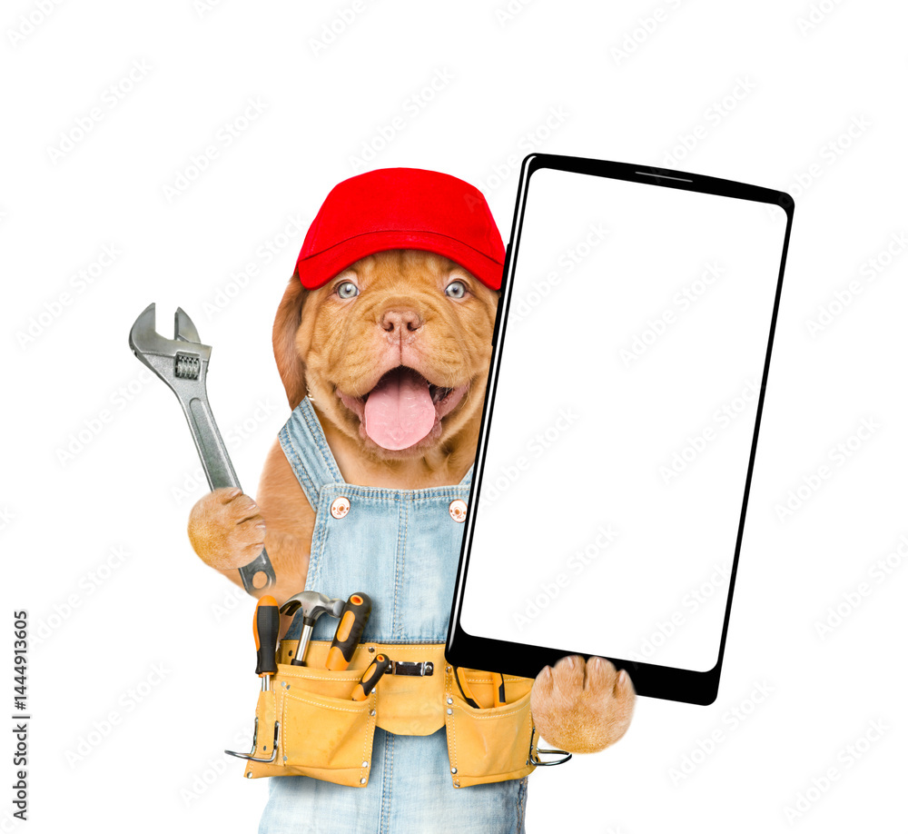 Aufkleber Funny Mastiff puppy wearing red cap and denim overalls with tool belt showing big smartphone with white blank screen in it paw. Isolated on white background