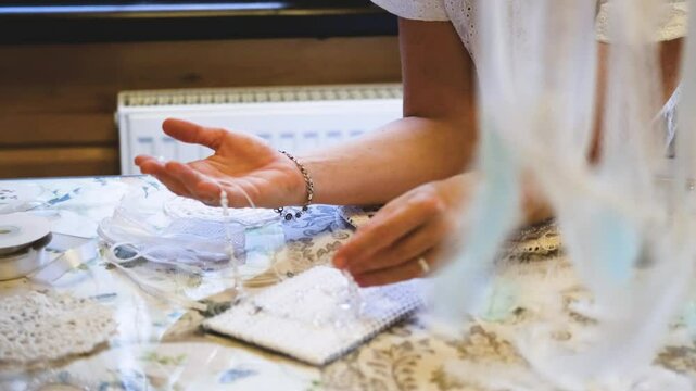 Woman making dreamcatcher from threads, feathers, beads and silk ribbons, making home decor items, handmade amulet